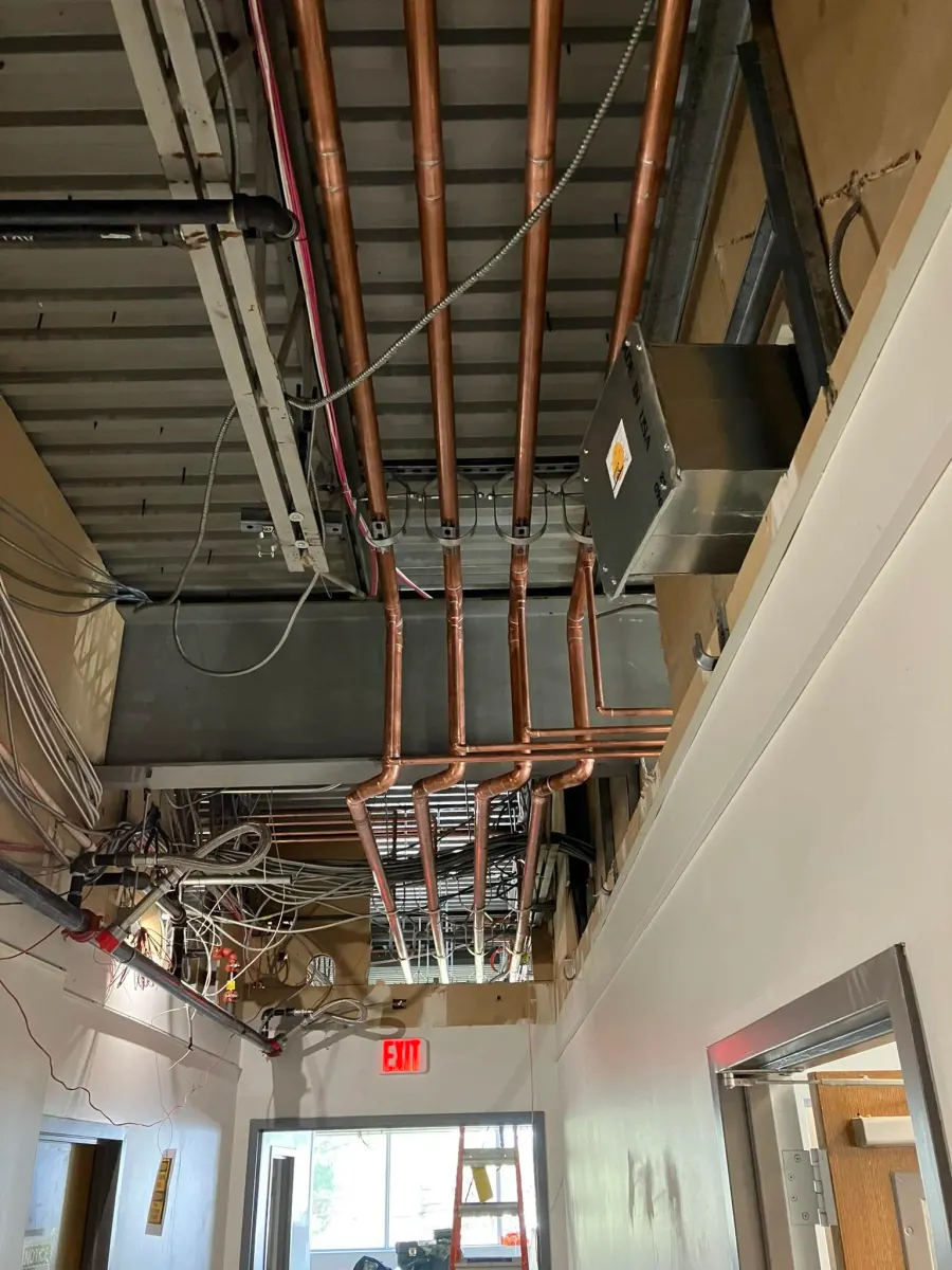 Overhead copper supply lines running through a commercial ceiling