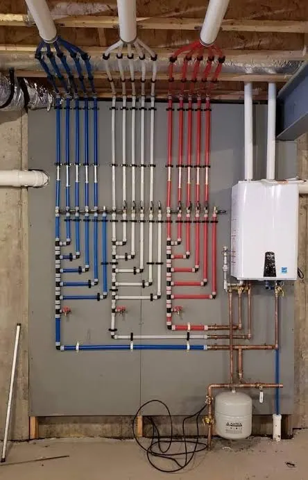 A colour-coded PEX manifold wall beside a tankless water heater