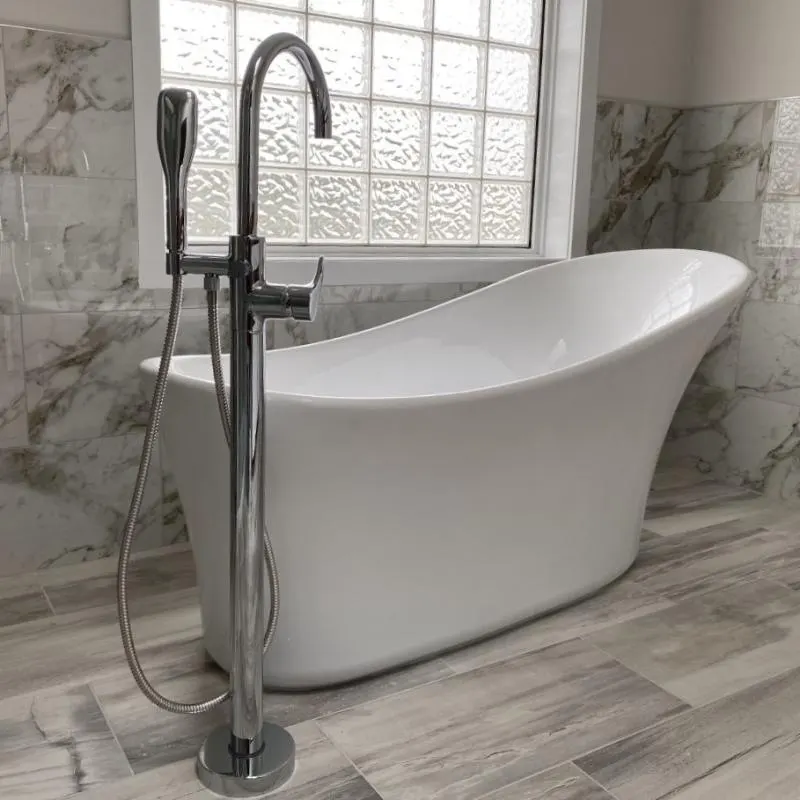 A white slipper tub with a freestanding chrome filler against marble